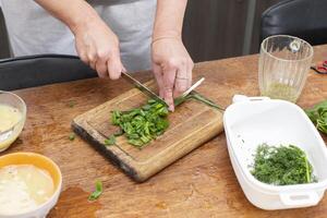 Hands chop green onions on a cutting board. photo