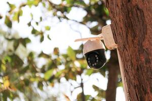 An old yet reliable CCTV camera mounted outdoors, exposed to sun and rain over the years, standing guard to ensure security for homes. Symbol of safety and modern surveillance technology. photo