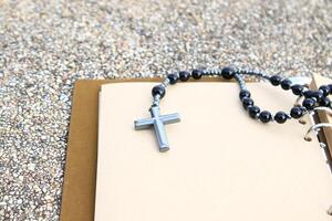 Shiny metal cross rests on an open brown notebook, symbolizing faith, reflection, and devotion. This image represents spiritual journaling, personal prayers, and religious contemplation. photo