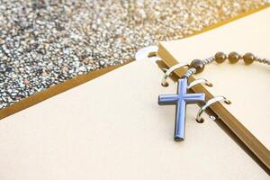 A shiny metal cross rests on an open brown notebook, symbolizing faith, reflection, and devotion. This image represents spiritual journaling, personal prayers, and religious contemplation. photo