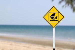 A clear yellow sign featuring a windsurfer symbol, designating an area for windsurfing activities, guiding sports enthusiasts to safe and approved zones. photo