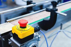 Simple red emergency stop button, Conveyor belt with empty cans. Production and preparation of conveyor equipment in the production of machines photo