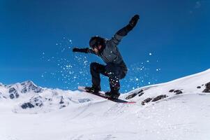 Flying snowboarder in the mountains, extreme sport. Wide angle on the flight in the jump of the snowboarder photo