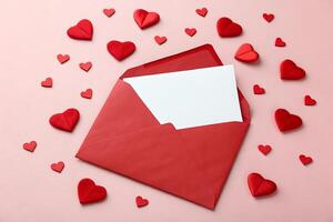 A red envelope, open and displaying a blank white card, is centered on a pale pink background. photo