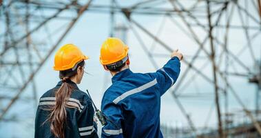 Engineers inspect power lines and discuss safety protocols at electrical substation site during daytime photo