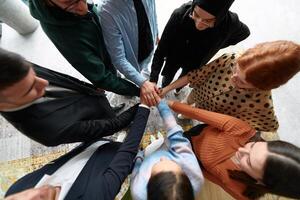 A group of business professionals joins hands in unity, symbolizing collaboration, strength, and shared commitment to success, captured from above photo