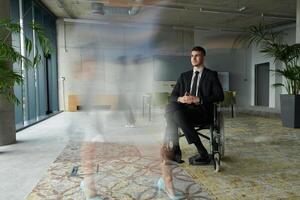 A businessman in a wheelchair navigating through a busy office, surrounded by his colleagues who are actively engaged in their work and collaboration photo