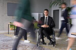 A businessman in a wheelchair navigating through a busy office, surrounded by his colleagues who are actively engaged in their work and collaboration photo