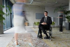 A businessman in a wheelchair navigating through a busy office, surrounded by his colleagues who are actively engaged in their work and collaboration photo