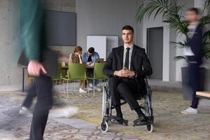 A businessman in a wheelchair navigating through a busy office, surrounded by his colleagues who are actively engaged in their work and collaboration photo
