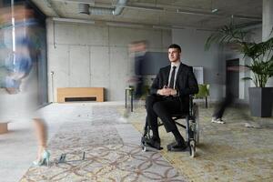 A businessman in a wheelchair navigating through a busy office, surrounded by his colleagues who are actively engaged in their work and collaboration photo