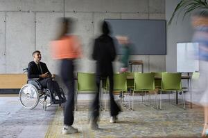 A diverse business team, working urgently around a conference table, collaborates on a meeting while their director, seated in a wheelchair, waits for their input photo
