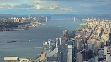 Hudson River with view of Manhattan and a prominent suspension bridge, aerial view of Hudson River, Manhattan, and a large suspension bridge under cloudy skies video