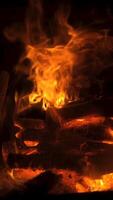 Bright flames flicker and twist above glowing embers in a cozy fireplace setting, creating a calming atmosphere during a quiet evening indoors. Vertical footage video