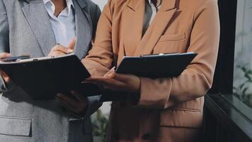 Two businesswomen are holding a clipboard and looking at something video