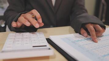 A woman in a business suit is using a calculator to calculate the amount of money video