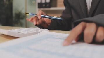 A person in a suit is using a calculator and pen to write on paper video