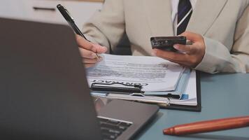 A man in a suit is holding a pen and a cell phone video