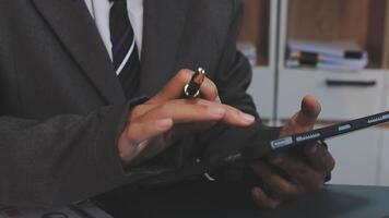 A man in a suit is using a pen to write on a tablet video