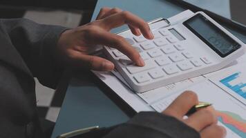 A person in a suit is using a calculator on a desk video