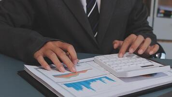 A man in a suit is using a calculator to look at graphs video