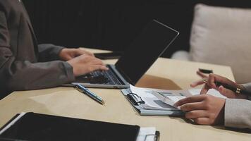 Two people sitting at a table with a laptop and papers video