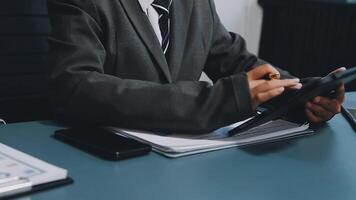 A man in a suit is sitting at a desk with a tablet video