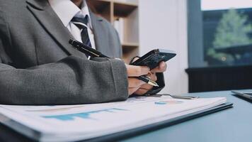 A man in a suit is using his phone while sitting at a desk video