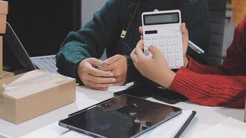 Two people are working on a laptop and a calculator video