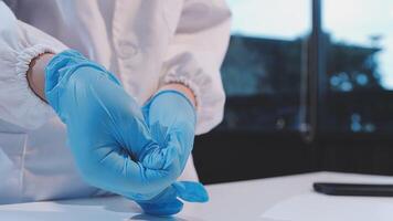 A person in a lab coat is holding a blue glove video