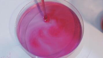 A pink liquid in a glass dish with a red liquid video