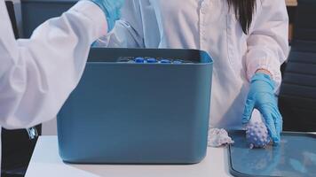 Two people in lab coats and gloves are working on a container video