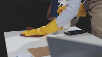 A person wearing yellow gloves is cleaning a desk video
