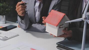 A woman holding a house model in front of a desk video