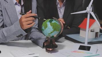 Business people working on a project with a globe and wind turbines video
