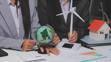 Two business people are working on a project with a globe and wind turbines video