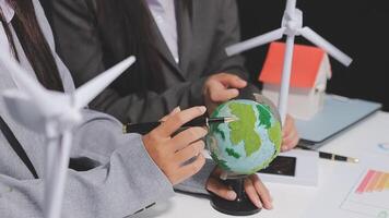 Two people are working on a globe with wind turbines video