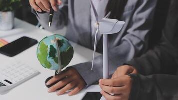 A person holding a globe and a wind turbine video