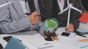 Business people working on a project with a globe and wind turbines video