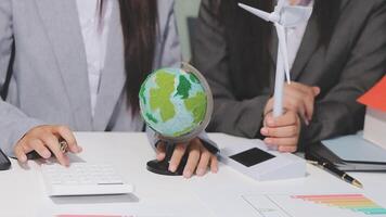 Two business people are working on a desk with a globe and calculator video
