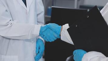 Two doctors shaking hands in a lab video