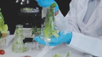 A person in a lab coat is holding a glass of water with vegetables in it video