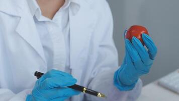 A person in a lab coat holding a red apple video
