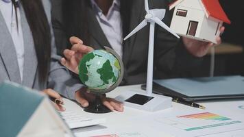 Business people working on a project with a house and wind turbine video