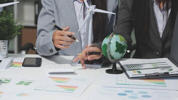 Business people working on a project with a globe and wind turbines video