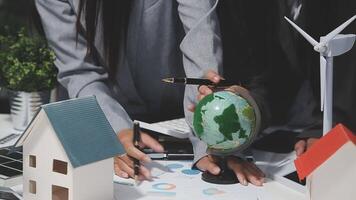 Business people working on a project with a globe and wind turbines video