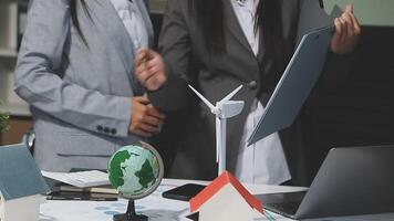 Two business people standing around a table with a laptop and a globe video
