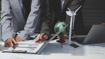 Business people working on a laptop with a wind turbine video