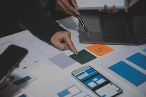 A person is using a laptop and pointing at a design photo