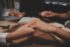 Hands of people holding hands at a table with bible photo